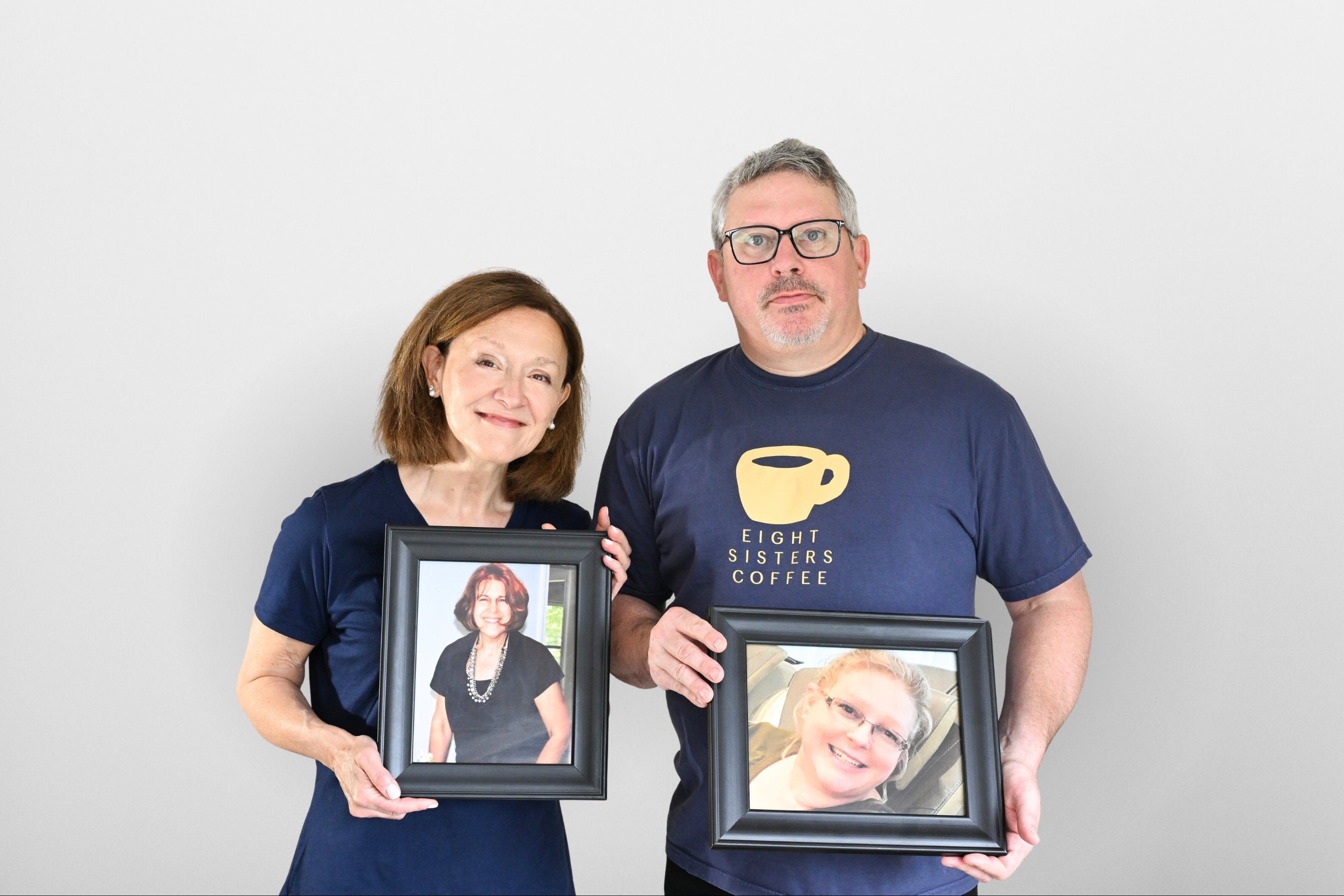 Eight Sisters Coffee Founders holding framed photos of sisters against a plain background