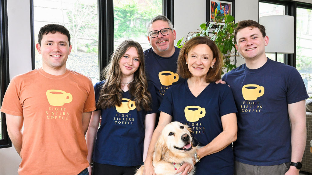Eight Sisters Coffee Team wearing matching t-shirts with a logo and text, standing indoors.