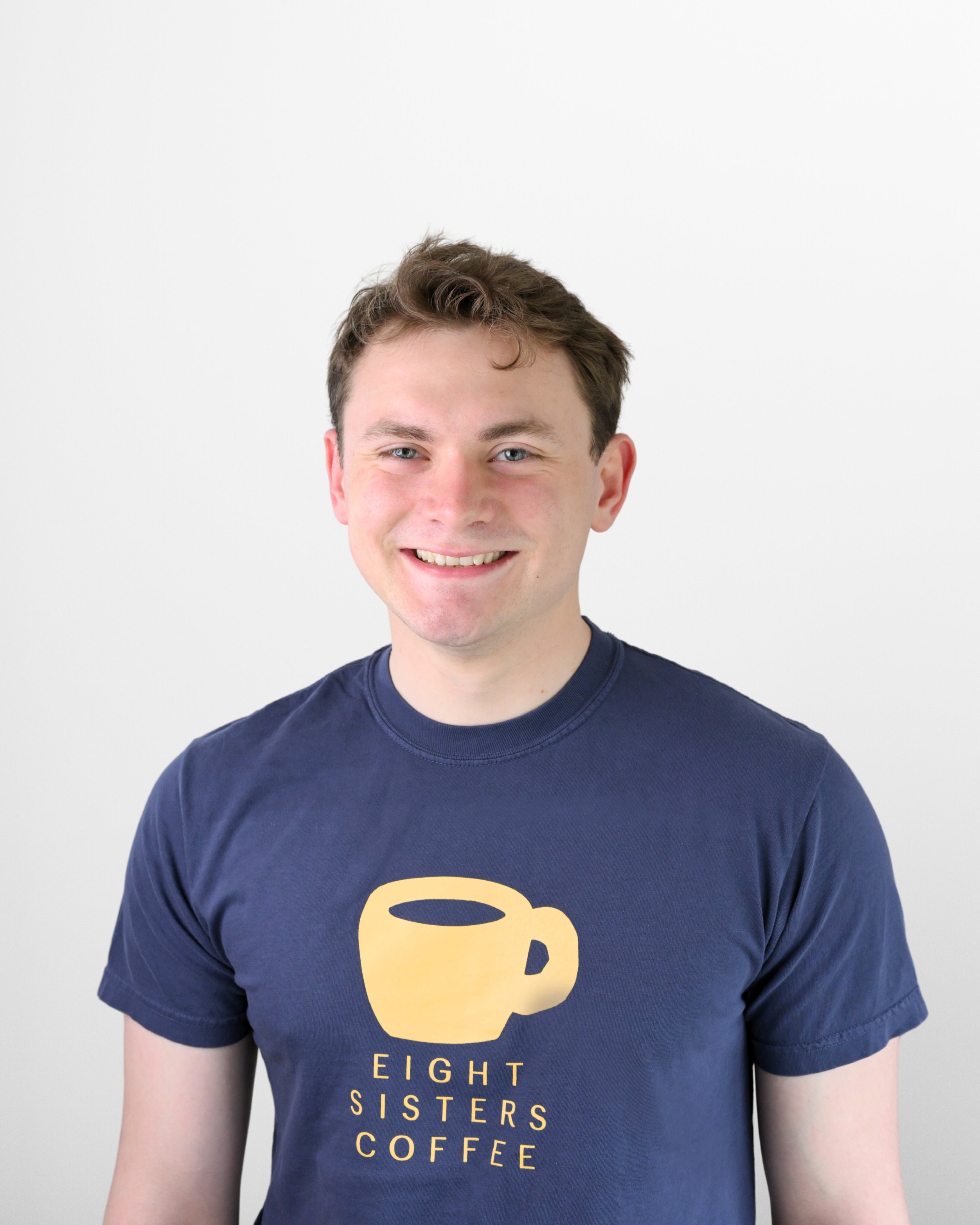 Ethan Sewall wearing an 'Eight Sisters Coffee' t-shirt against a white background