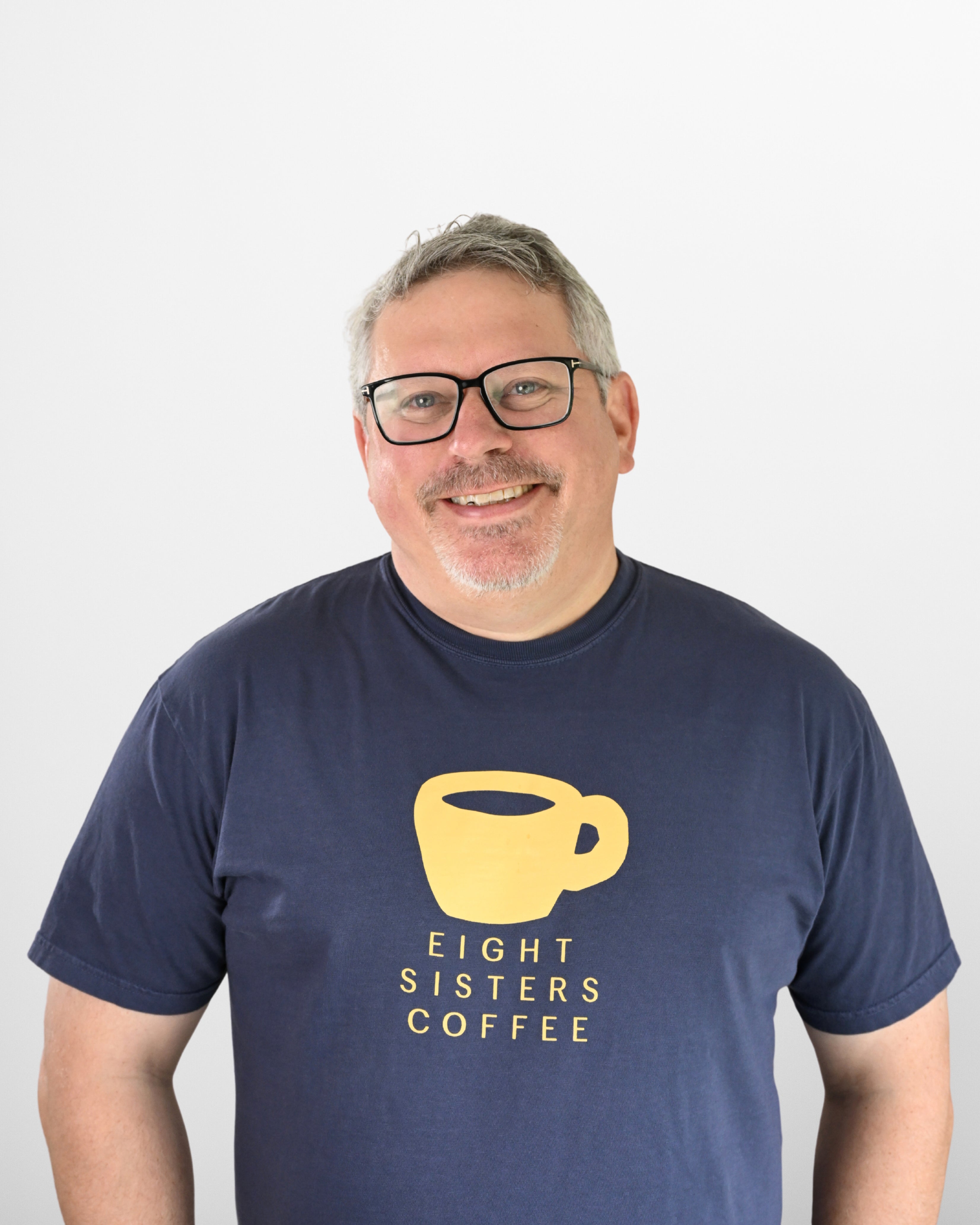 Jeremy Sewall wearing a navy blue t-shirt with 'Eight Sisters Coffee' logo on a white background
