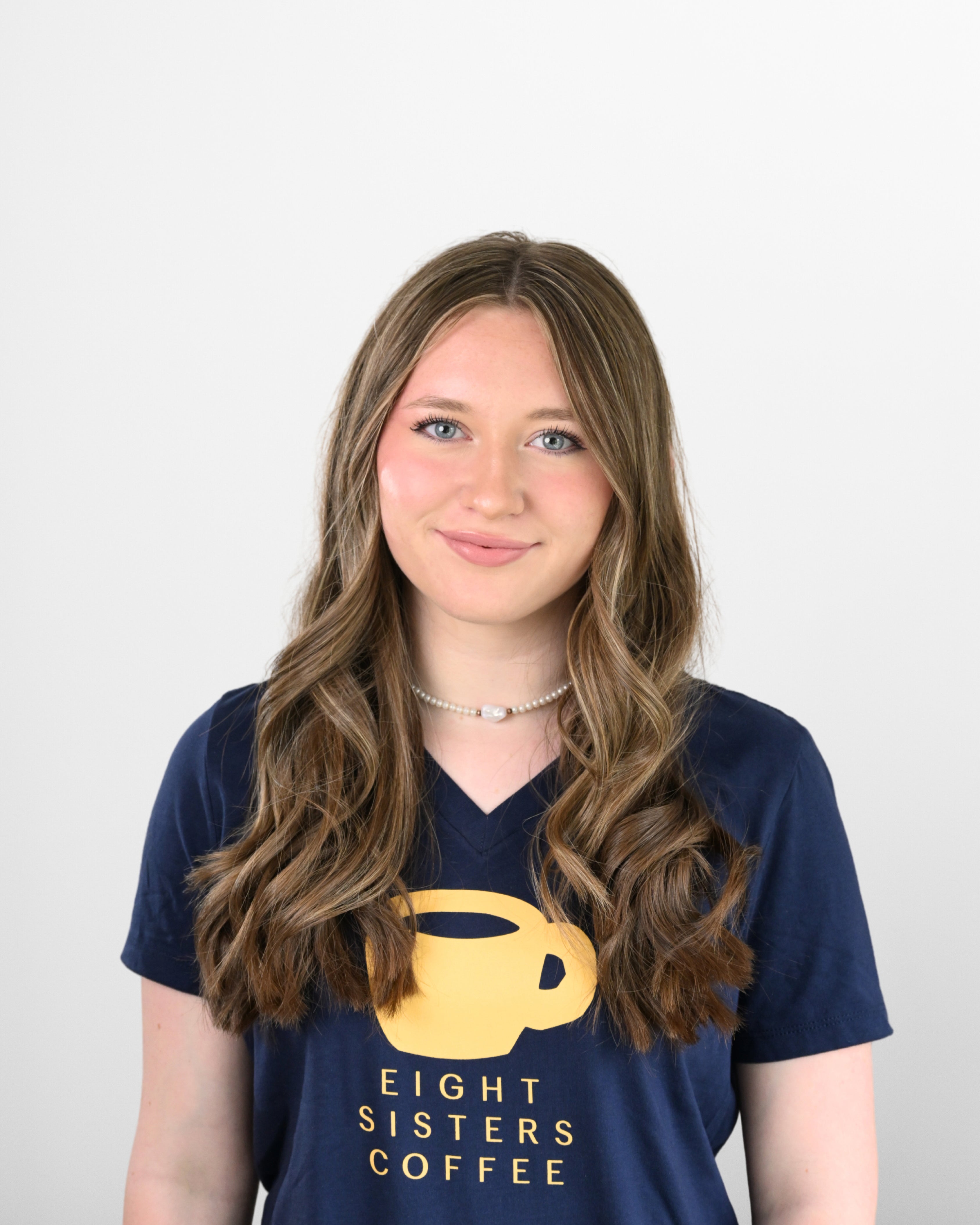 Sophia Sewall wearing a navy blue t-shirt with 'Eight Sisters Coffee' logo on a white background
